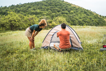 boyfriend and girlfriend set up a tent in nature ready for camping