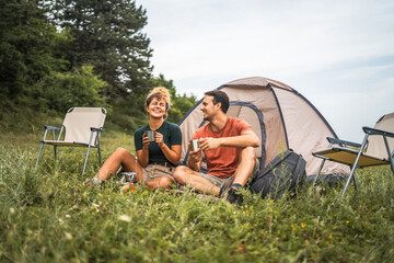 couple in love sit on the grass enjoy camp with coffee and talk