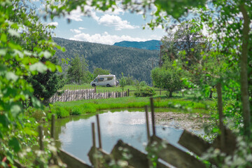 Small campervan or RV parked in beautiful picturesque surrounding in front of a lake and before beautiful mountain backdrop. Epic view of camper van in nature