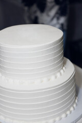 A view of a two tiered cake with smooth white icing.