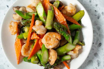 A top down view of a plate of shrimp and asparagus.