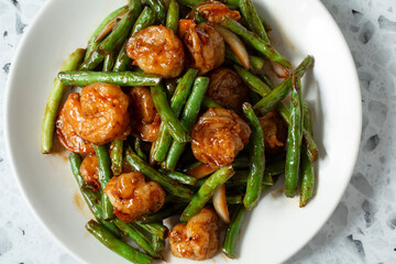 A top down view of a plate of green beans and shrimp.