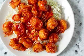 A top down view of a plate of orange shrimp.
