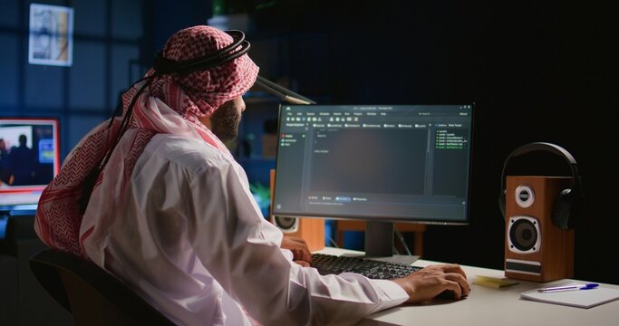 Trained muslim engineer writing code on computer screen while in office using Java programming languages. Middle Eastern developer working on fixing database errors while working from personal office