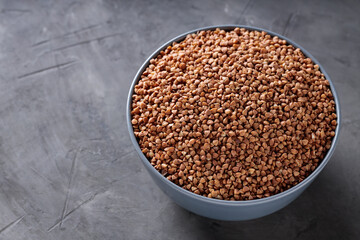 Organic Dry Buckwheat Grains in Bowl on Concrete, Copy Space