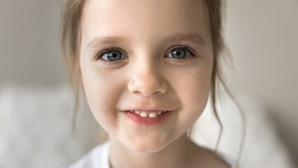 Close up face of pretty preschooler 4s girl, having beautiful appearance, smiling looking at camera revealing baby teeth, advertises dental services for little patients. Alpha generation kid portrait