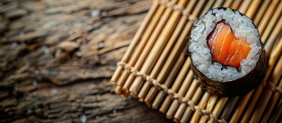 Single piece of sushi with salmon and rice on bamboo mat. Close-up food photography. Japanese cuisine and seafood concept. Banner with copy space