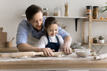 Dad and little 4s daughter wear aprons cooking pastries, flattening homemade dough for buns, enjoy...