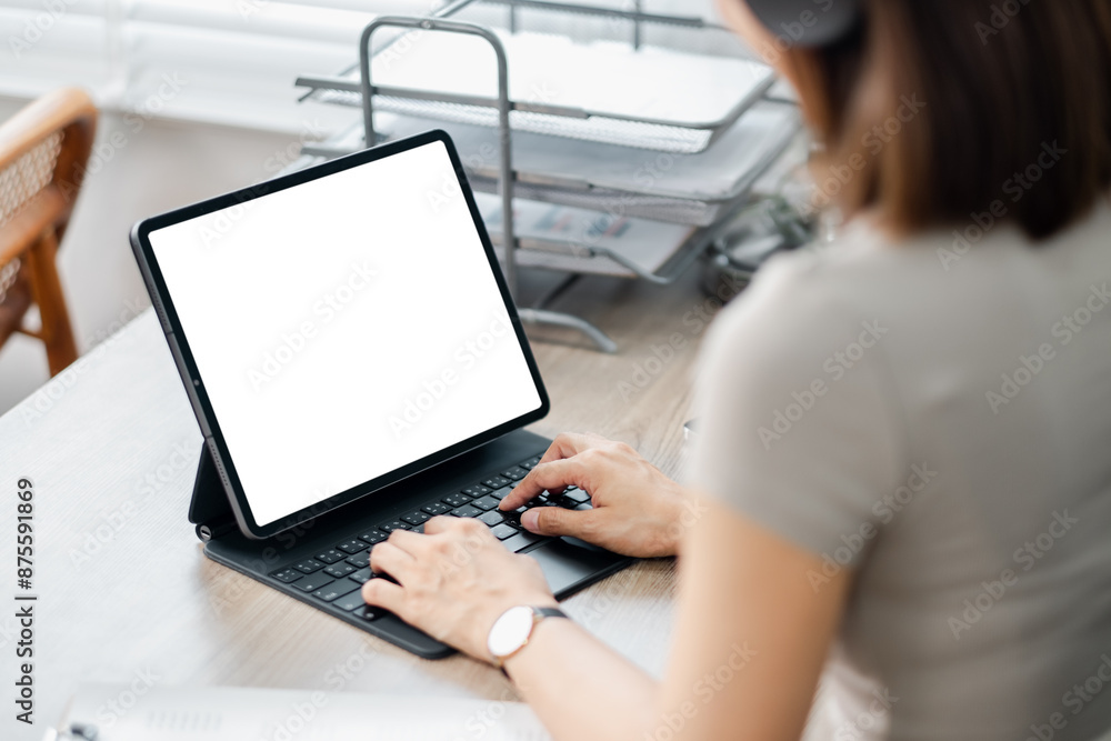 Poster woman typing on a tablet with a keyboard in a home office setting. blank screen for copy space. mode