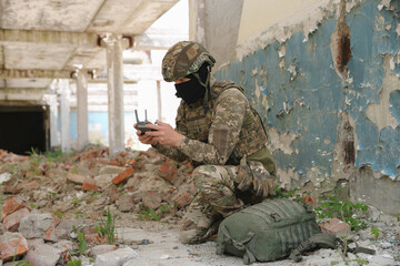 Fototapeta premium Military mission. Soldier in uniform with drone controller inside abandoned building
