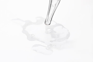 Glass pipette and transparent liquid on white background, closeup