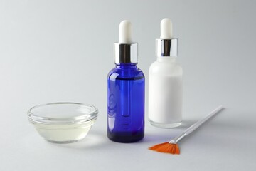 Bottles of chemical peel, bowl with liquid and brush on light background, closeup. Peeling procedure