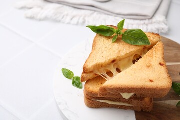 Pieces of toasted bread with melted cheese and basil on white table, space for text