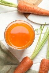 Healthy juice in glass and fresh carrot on white wooden table, flat lay