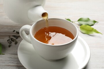 Pouring refreshing green tea into cup at grey wooden table, closeup