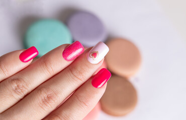 Beautiful female hand with pink manicure nails, heart and Valentine's day design

