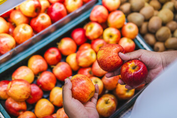 High-angle Shot of a Latino Man Selecting Red Apples in a Shopping Center, Benefits of Apples, Mental and Physical Health, Healthy Fitness Lifestyle