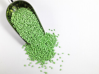 Matcha green masterbatch granules in scoop on white background.Color pigment carrier polymer in...