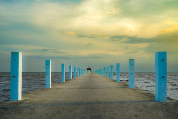 pier stretching into the sea at sunset with a serene sky and clouds above the ocean