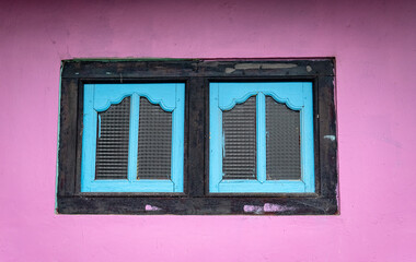 a pair of blue and black vintage windows with pink walls