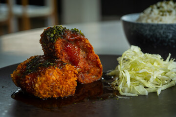 Japanese food menchi katsu メンチカツ and rice, served with black plate and white bowl, over stone tile table, cafe environmen