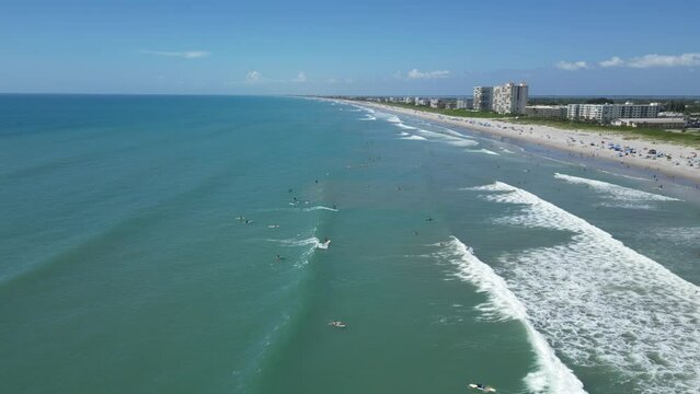 Still shot of surfers enjoying the waves on a beautiful sunny beach day near Lori Wilson Park in Cocoa Beach, Florida