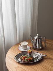 Delicious breakfast, brunch - a cup of cappuccino, boiled egg, avocado and salmon sandwich on a wooden table