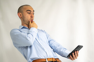 Young businessman very surprised looking at his phone screen