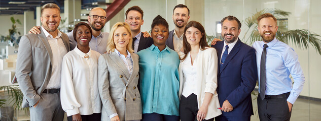 Group of business multiethnic people men and women looking cheerful at camera and smiling indoors. Company employees or group of staff standing in office confidently. Team work concept. Banner.