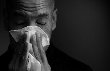 blowing nose after catching a cold with grey background stock photo	