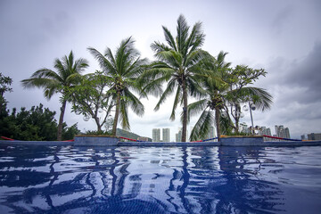 infinity pool in a summer beachfront hotel resort at beautiful tropical landscape. Tranquil beach holiday vacation background. Amazing island sunset beach view, palms swimming pool