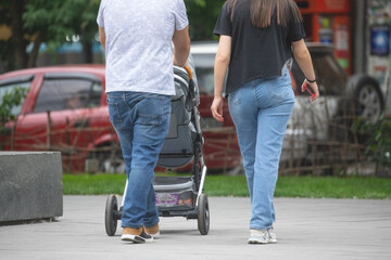 Couple walking in the city with a baby in stroller.