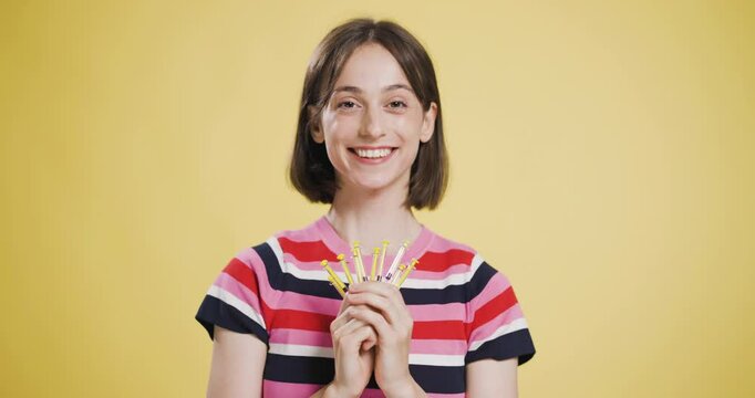 Joyful young woman holding yellow syringes with a content smile on a yellow background