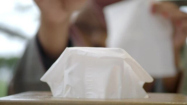  hand pull out a piece of tissue from tissue paper box 