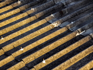 Abstract background of an old, weathered corrugated cement roof with a strong diagonal pattern...