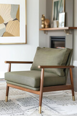 A mid-century modern-style wooden armchair with brass legs and green fabric cushion, placed in an elegant living room setting with minimalist decor. The chair is centered on the floor against a wall.