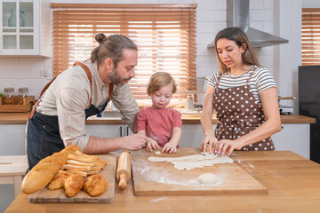 Beautiful cute family having fun while cooking together in the kitchen at home. Family with child in kitchen having breakfast	