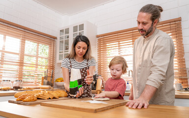 Beautiful cute family having fun while cooking together in the kitchen at home. Family with child in kitchen having breakfast	