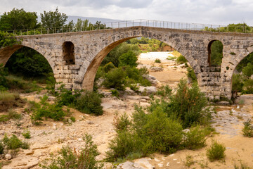 Obraz premium The Pont Julien, famous Roman bridge in Bonnieux, Luberon, France, dates back 2000 years. It spans the Calavon River in three arches