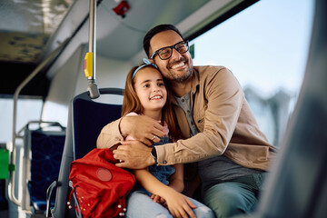 Happy father embracing his daughter while riding in  bus.