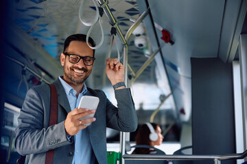 Businessman using mobile phone while commuting to work by bus.