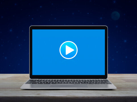 Play button on modern laptop computer moniyor screen on wooden table over fantasy night sky and moon, Business music online concept
