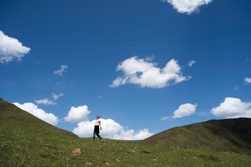 one Asian woman walking on Tibetan Plateau under blue sky