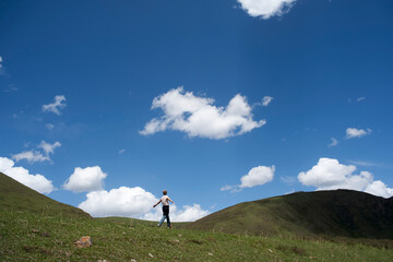 one Asian woman walking on Tibetan Plateau under blue sky