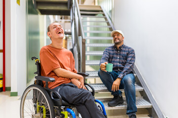 Freelance and disabled coworker laughing during coffee break at coworking