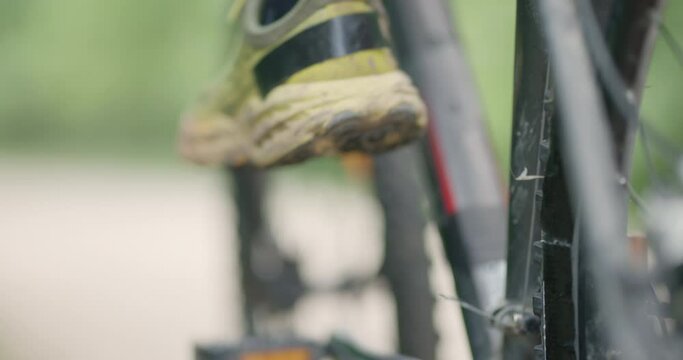 Abstract mountainbiker getting ready to ride. Man riding a mountainbike on a dusty dirth road path. Closeup pedal shoe and gear shift. Recorded at 120 fps on cinema camera.
