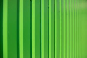 Green fence. Ribbed metal. Light green background.
