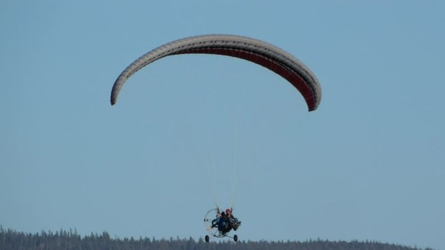Flight on paraglider with motor and a wing parachute on a summer day