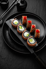 Philadelphia Black Roll. Sushi composition on black background. The Art of Japanese Cuisine. Food photography for menu and sushi bar decoration