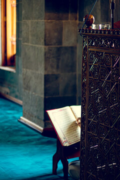 Islamic or Ramadan themed background photo, A Quran on a stand in a dimly lit mosque, illuminated by soft light, symbolizing spirituality and reflection, 